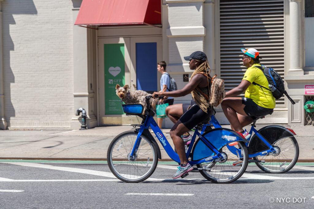 Two people riding CitiBikes on NYC Street