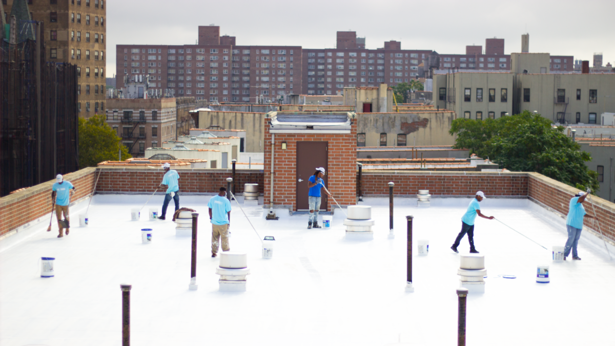 NYC CoolRoofs trainees coat a rooftop with white reflective paint
